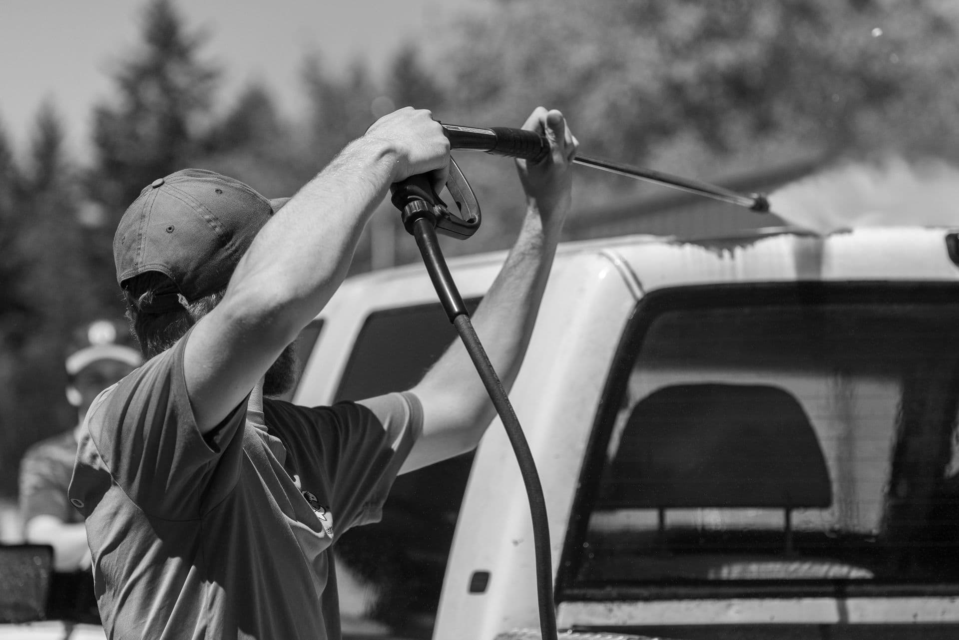 Worker pressure-spraying a truck outdoors